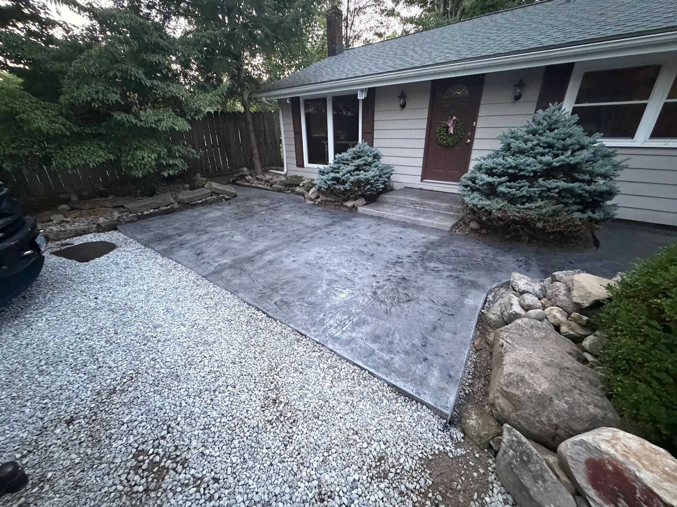 Textured concrete entry with curved edges beside the front steps.